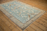 Angled shot of a vintage Malayer rug with stylized bird and dragon motifs on a sky blue field.
