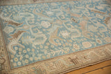 Corner view of a distressed Malayer rug's low pile, showing stylized dragon and bird motifs.