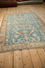 Angled view of a distressed Malayer rug showing the low pile and stylized dragon motifs.