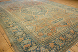 Low angle view highlighting the even wear and dusty blue floral borders of an antique Farahan Sarouk carpet.