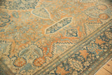 Close-up of the even wear on an antique Persian rug's terracotta field and dusty blue floral border.