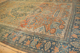 A low-angle view of the antique Farahan Sarouk's worn pile, with terracotta, rust, and dusty blue floral designs.