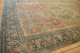 Angled view of an antique Farahan Sarouk showing its navy floral border and rust-colored field.