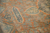 Intricate cypress and blossom motifs in rust and dusty blue on the evenly worn pile of an antique carpet.