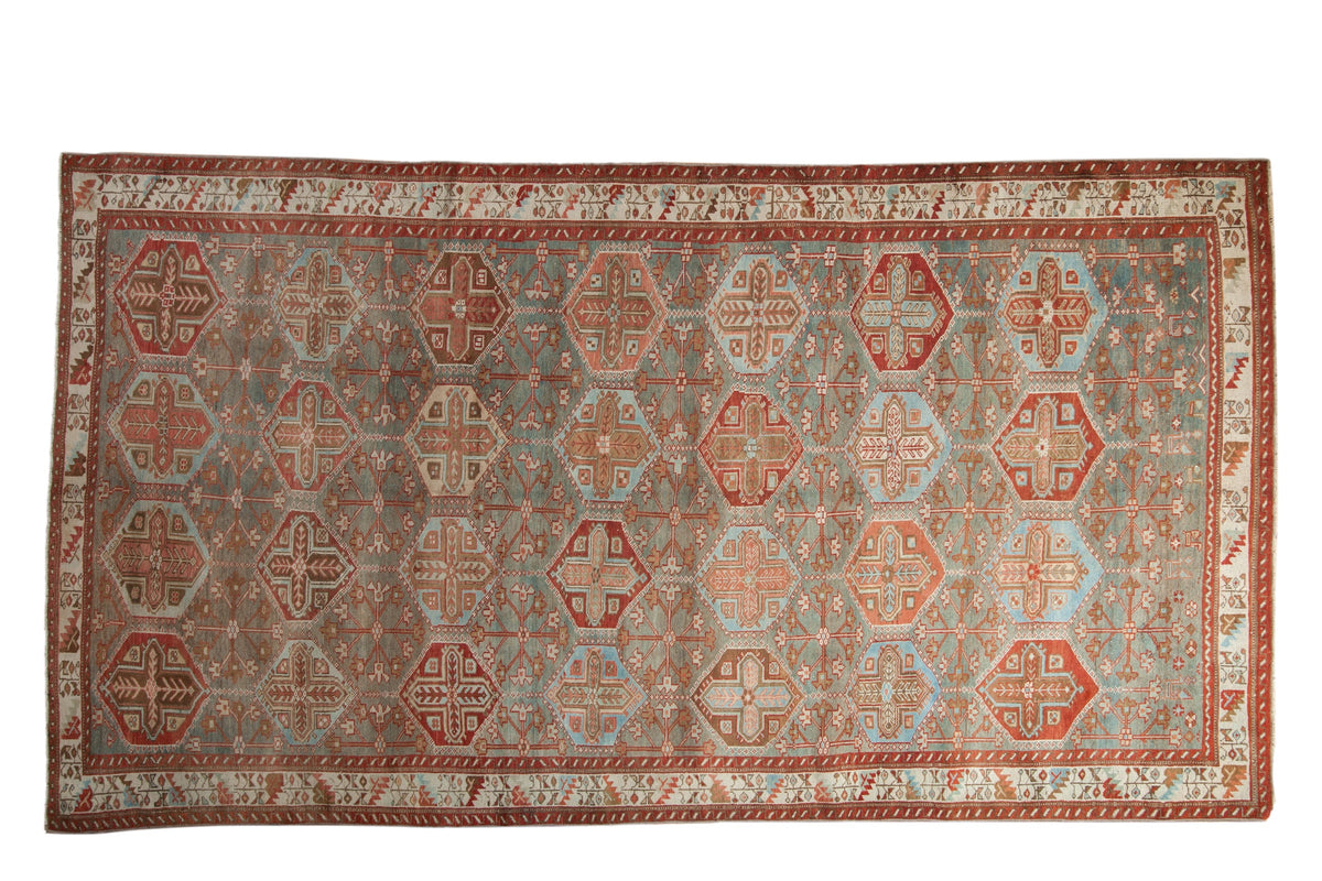 Vintage distressed Baktiari carpet with repeating hexagonal panels in muted pomegranate red and slate blue.