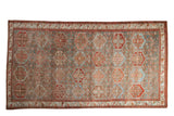 Vintage distressed Baktiari carpet with repeating hexagonal panels in muted pomegranate red and slate blue.