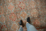 Worn texture of repeating hexagonal panels in pomegranate red and slate blue on a vintage Baktiari carpet.