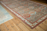 Angled view of a vintage Baktiari carpet's repeating hexagonal panels and serrated leaf border.