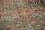 Close-up of a vintage Baktiari carpet's low pile showing hexagonal plant motifs in red and blue.