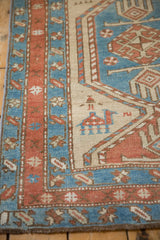Low pile of an antique Serab rug showing a camel motif beside geometric blue and madder red borders.