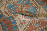 Stylized camel and herdsmen figures in blue and red on the sand-colored ground of an antique Serab rug.