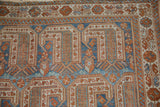 Corner detail of a vintage Afshar rug showing intricate geometric borders in terracotta, blue, and ivory.