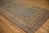 Angled view of a distressed Malayer runner's low pile and geometric motifs in blue and rust.