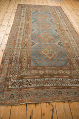 Full length perspective of a distressed Malayer runner with a column of rust diamond medallions.