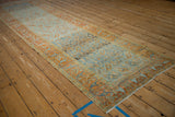 Angled view of a distressed Afshar runner with terracotta botehs on a heavily abrashed blue ground.