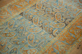 Angled detail view of the distressed texture and terracotta boteh pattern on a dusty blue ground.