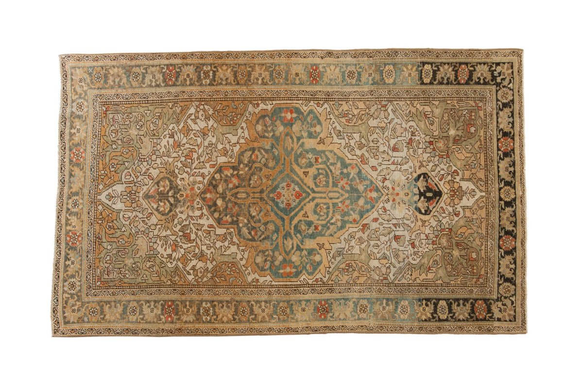 Vintage distressed Sarouk rug with an oversized teal medallion on an ivory field of blossoms and vines.