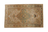 Vintage distressed Sarouk rug with an oversized teal medallion on an ivory field of blossoms and vines.
