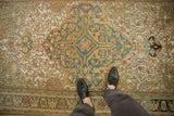 Even wear across the knot heads of a Sarouk's dusty teal shield medallion.