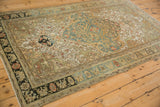 Angled view of the distressed Sarouk rug's traditional design in dusty teal, moss green, and ivory.
