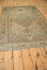 Angled view of the vintage distressed Sarouk rug, highlighting the texture and muted teal pattern along its length.