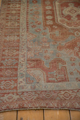 Low-angle view of the worn knot heads and geometric borders on a distressed Persian Bijar rug.