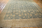 Angled view of a distressed Bijar carpet highlighting the abrash color variation across its floral field.