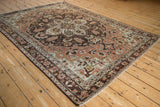 Angled view of a distressed Hamadan rug with a charcoal and copper rose medallion.