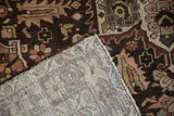 Folded corner of a distressed Hamadan carpet showing the detailed hand-knotted back weave.
