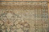 Worn corner of a distressed Persian Mahal rug with sand and brown spiraled arabesques.