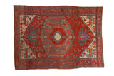 Antique Northwest Persian rug with concentric hexagonal medallions in brick red, sky blue, and faded ivory.