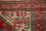 Meandering vine border in brick red and sky blue on an antique Persian rug with a low, worn pile.