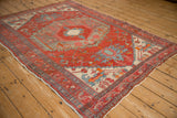 Angled perspective of an antique Northwest Persian rug's geometric medallion and brick red field.