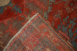 Corner of an antique Persian rug folded to show the hand-knotted weave and rich wool pile.