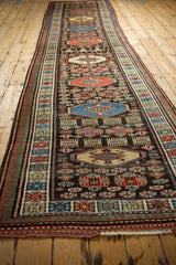 A long perspective view showing the single column of repeating geometric medallions on a vintage Kurdish runner.
