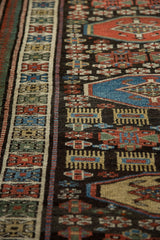 Detailed weave of a vintage Kurdish runner showing geometric border and finned design elements.