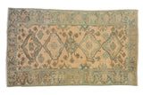 Distressed vintage Malayer carpet with a medallion column and floral border in faded blue and cream.