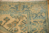Corner of a distressed Malayer rug showing the wide floral border and low-pile texture.