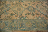 Close view of the worn texture across the wide floral border and geometric medallions of a Malayer rug.