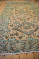 Distressed vintage Malayer rug viewed lengthwise, showing worn texture and column of medallions.