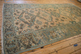 Corner of a distressed Malayer carpet showing the wide serrated leaf border and worn pile.