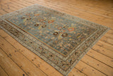Angled perspective of a vintage Malayer rug's decorative floral pattern and slate blue field.