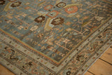 Corner detail of a distressed Malayer rug showing the meandering serpent border and low, even pile.