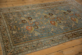 Side angle view of the distressed Malayer rug's slate blue field and interconnected floral motifs.