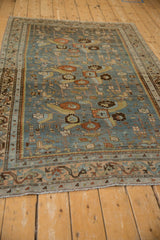 Angled view down the length of a distressed Malayer rug, highlighting its even wear and slate blue color.