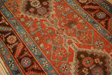 Stepped geometric motifs and floral patterns on a brick red and sapphire blue antique Persian rug.