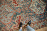 Distressed low pile and geometric motifs in dusty blue, cherry red, and sand on a vintage Malayer rug.