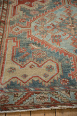 Close view of a Malayer carpet's serrated motifs, distressed pile, and scattered white knots.
