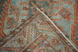 A folded corner of the vintage Malayer carpet reveals the hand-knotted foundation and low pile.