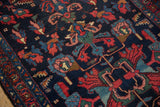 Vintage Mehreban rug detail with intricate rose, sky blue, and red serrated blossom motifs on navy.